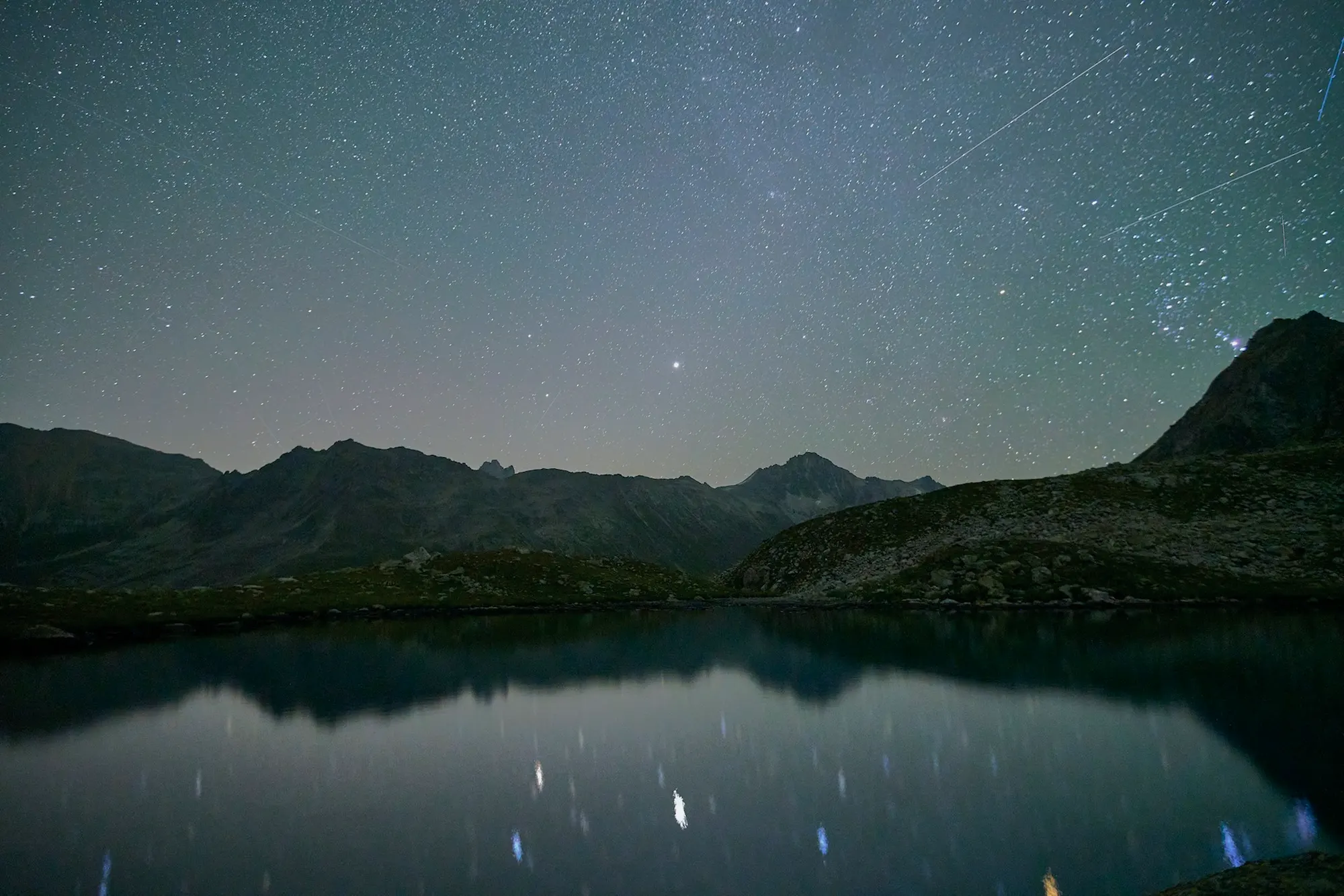 A starry night sky over a mountain lake